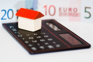 casita con calculadora y billetes de euro representando una compra-venta